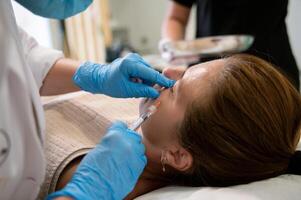 Anonymous beautician administering injection to cheek of female client photo