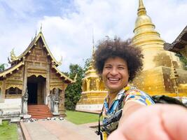 Exuberant traveler shares a moment with a smartphone selfie at golden temple, vacation activities and adventure concept photo