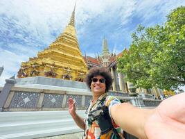 Tourist takes a selfie with a beaming smile in a historic golden temple in Asia. photo