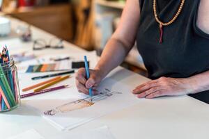 High angle of a fashion designer drawing a fashion sketch with colorful pencils photo