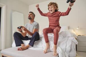 Excited kid with father playing videogame photo