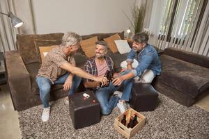 Men smiling and clinking beer bottles at home photo