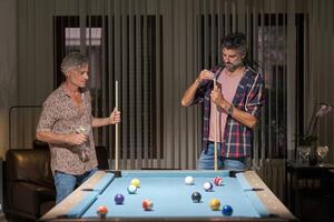 Senior men standing near pool table photo