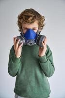 Kid in half face respirator and looking at camera in gray studio photo