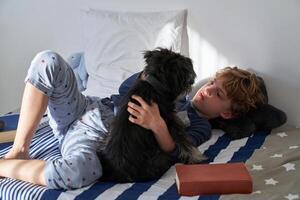 Calm boy lying with dog on bed photo