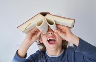 Funny boy with mouth opened looking through binoculars from book photo