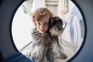Curious boy with dog looking in washing machine photo