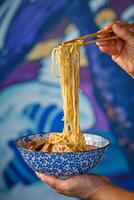 Crop person using chopsticks while eating Japanese noodle soup photo