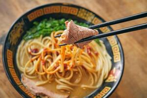 Tasty ramen with soft pork slice between food sticks photo