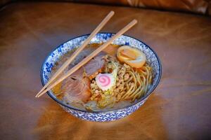 Asian noodle soup with chopsticks in bowl photo