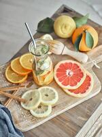 Slices of fruits and bottle of lemonade on cutting board photo