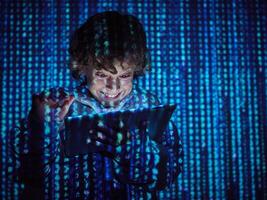 Grinning hacker pressing on tablet photo