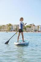 Child on SUP board floating in sea during training photo