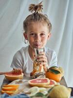 Smiling little boy sitting at table and drinking juice photo