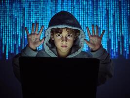 Programmer boy with hands up at laptop photo