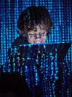 Smiling hacker with tablet on binary code background photo