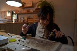 Concentrated craftswoman using soldering torch during jewelry ma photo