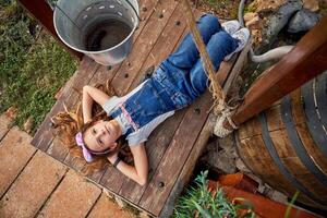 Dreamy girl on wooden platform in rural yard photo