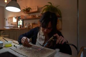 Focused female artisan creating handmade accessories in workshop photo