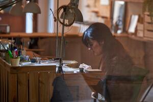 Attentive ethnic female goldsmith working with various tools in photo