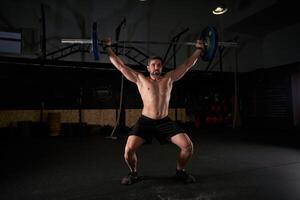 Man with raised hands with barbell while doing weightlifting exe photo