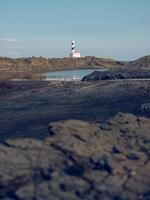 Lake and lighthouse in rocky terrain photo