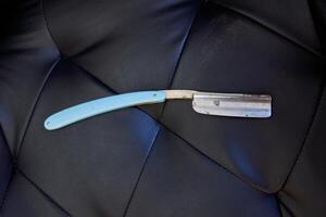 Dangerous sharp razor on leather sofa photo