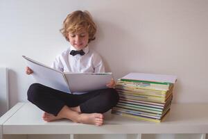 Cheerful boy reading book on table photo