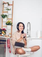 Female in headphones using tablet while relaxing with coffee photo