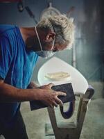 Serious surfboard shaper working using sandpaper in workshop photo