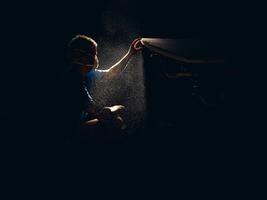 Man checking smoothness of surfboard in dark workshop photo