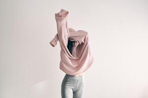 Woman covering face with sweater in studio photo