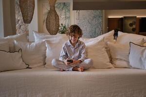 Cheerful boy using smartphone on sofa photo