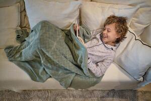 Delighted boy reading book on sofa photo