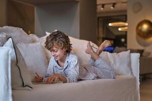 Cheerful boy creating sketch in paper notepad at home photo