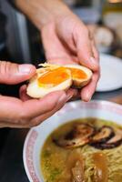 Crop person adding boiled eggs to ramen photo