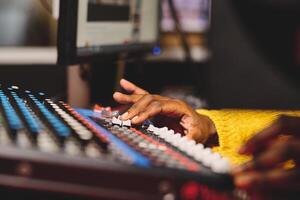 Crop ethnic female radio host using mixing console in studio photo