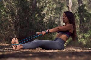 Determined young ethnic woman doing stretching exercise with res photo