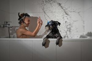 Smiling boy splashing water in tub with dog photo