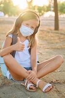Girl in mask sitting on ground and showing thumb up photo