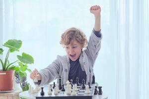 Cheerful preteen boy showing fist up gesture while winning chess photo