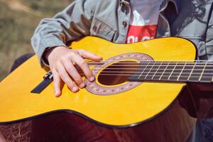 Crop unrecognizable child playing guitar in nature photo