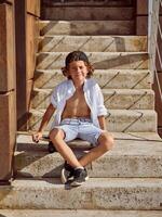 Boy sitting on skateboard on stairs of building photo