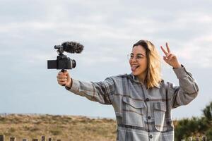 Happy female blogger showing tongue while shooting on camera photo