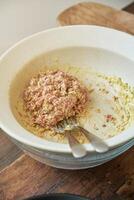 Ceramic bowl with minced raw meat and sauce on wooden table photo