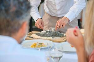 Unrecognizable waiter serving dish during dinner photo