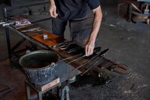 Maestro con varios herramientas haciendo vaso en fábrica foto