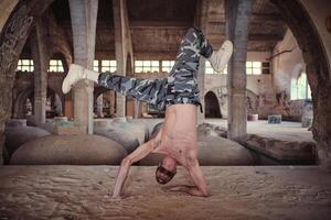 Muscular man performing cricket movement of breakdance in abandoned building photo