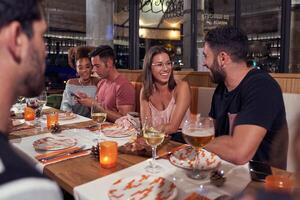 Diverse company of friends chilling in cozy pub in evening photo
