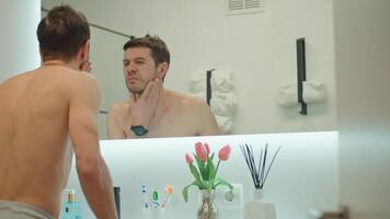 Shirtless man checking skin in front of mirror in bathroom video